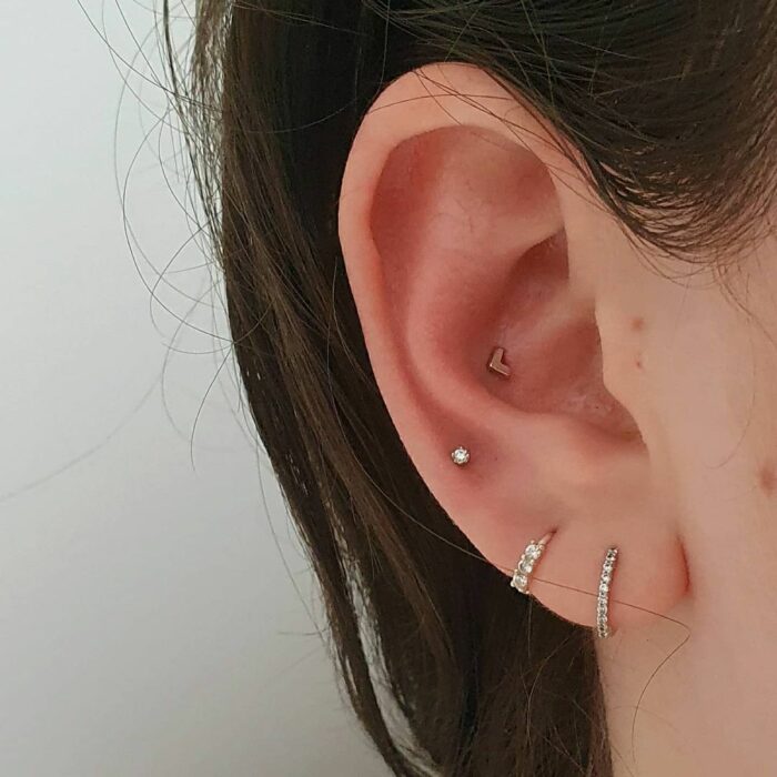 Chica con pequeños pendientes en los oídos; 13 Creativas maneras de llevar más de un piercing en el oído