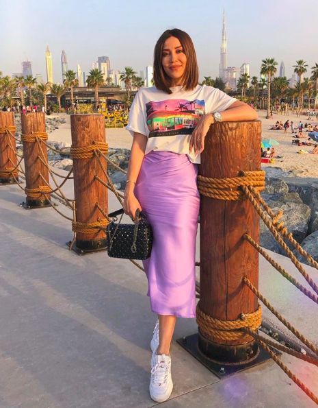 Chica con melena corta recta usando blusa blanca con falda de satín morada