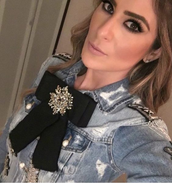 Melissa de JNS con camisa de mezclilla y moño negro con broche plateado