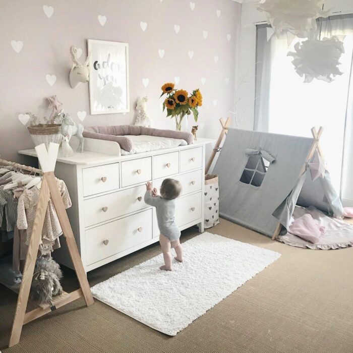 Cuarto de un bebé decorado con un cambiador, un tipi y un pequeño clóset para pañaleros hechos de palets