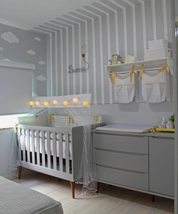 Decoración del cuarto del bebé en tonos grises, con una cuna junto a la ventana y un cambiador