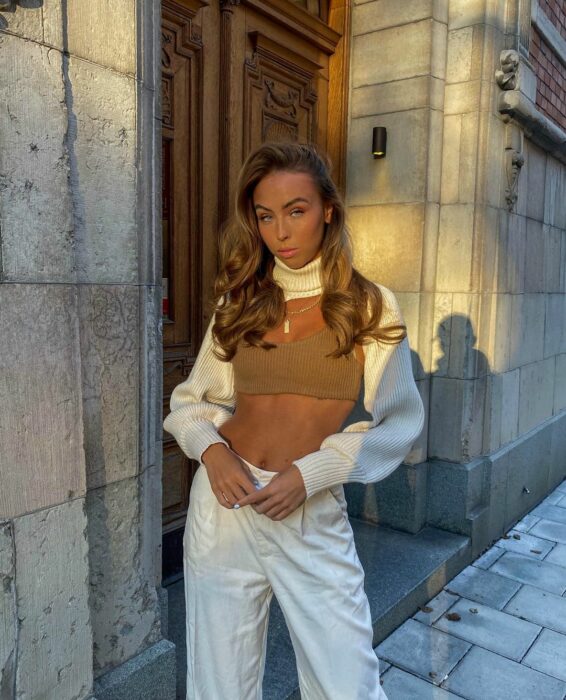 Chica rubia y bronceada con pans blancos y suéter de Zara