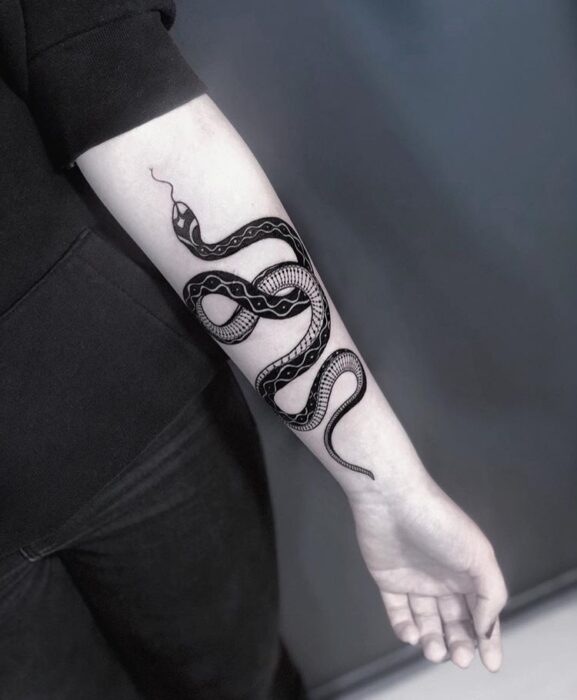 Chica con tatuaje de serpientes en color negro en el antebrazo