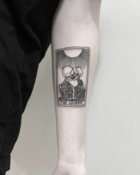 Chica con tatuaje en el antebrazo en forma de calaveras abrazándose