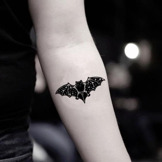 Chica con tatuaje en el antebrazo en forma de murciélago