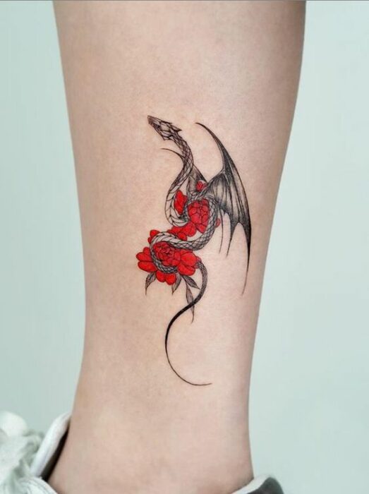 Chica con tatuaje de un dragón sosteniendo flores rojas