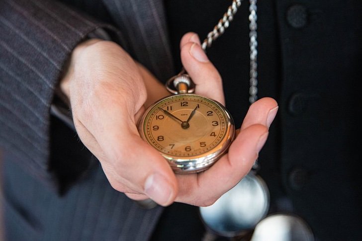 Mano sosteniendo un reloj de bolsillo dorado