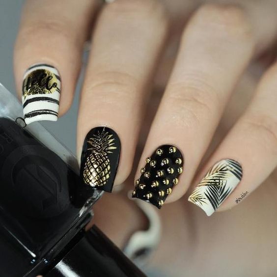 Manicura en blanco y negro decorada con puntos dorados y estampados de piñas