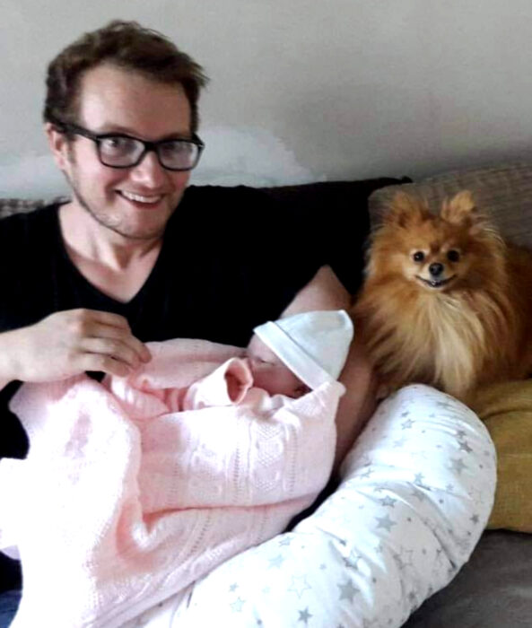 Perros sonriendo; perrito pomerania peludo color café con dueño y bebé