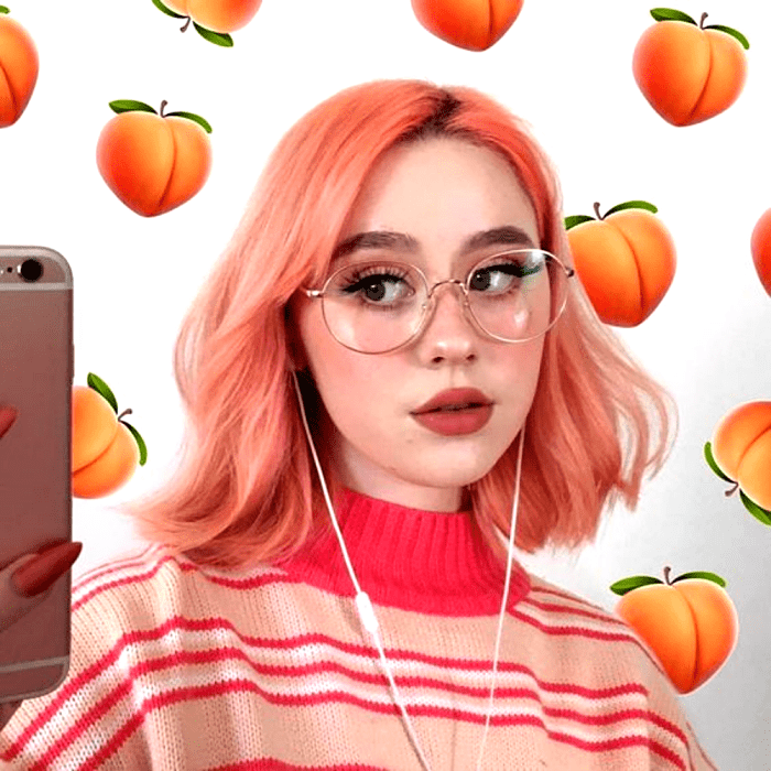 chica de cabello rosa durazno, lentes grandes, suéter rosa con fucsia de rayas