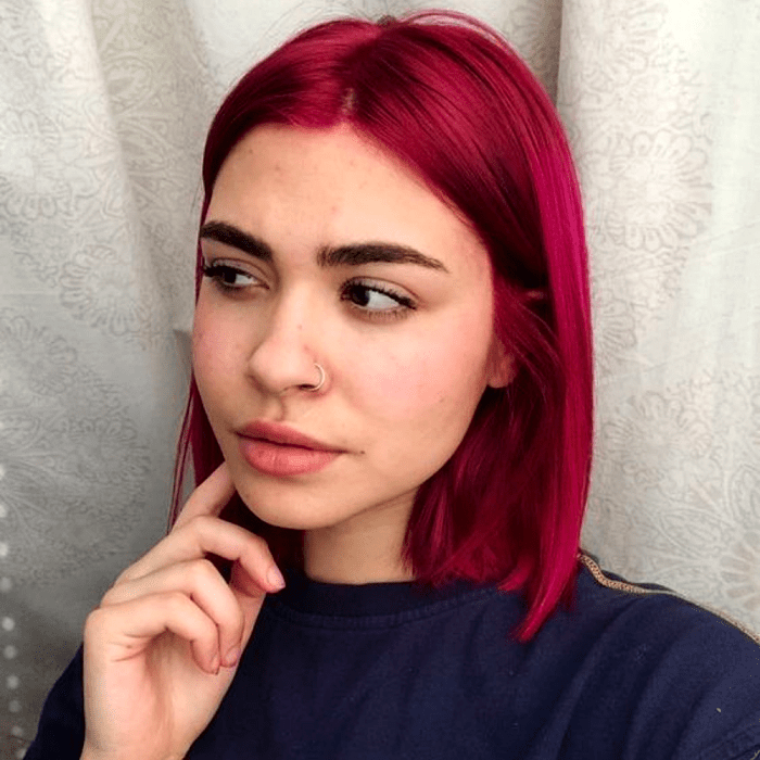 chica de cabello corto teñido rosa fucsia intenso, usando una camiseta azul marino