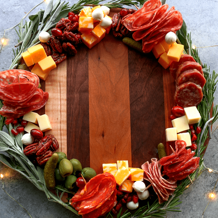 tabla de quesos, embutidos, charcutería, uvas, salami, jamón serrano, con estilo navideño