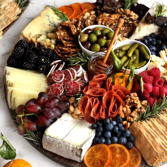 tabla de quesos, embutidos, charcutería, uvas, salami, jamón serrano, con estilo navideño