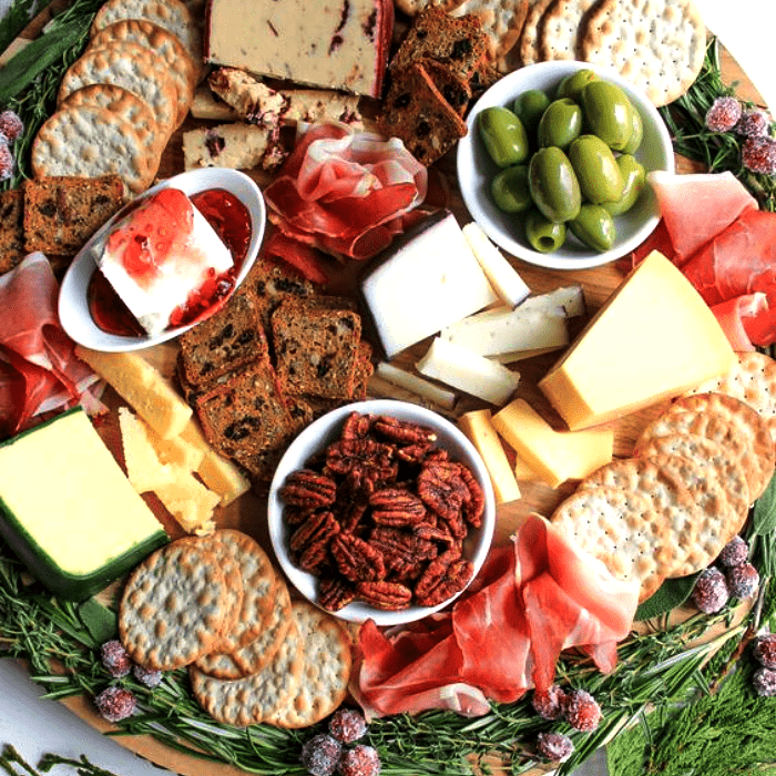 tabla de quesos, embutidos, charcutería, uvas, salami, jamón serrano, con estilo navideño