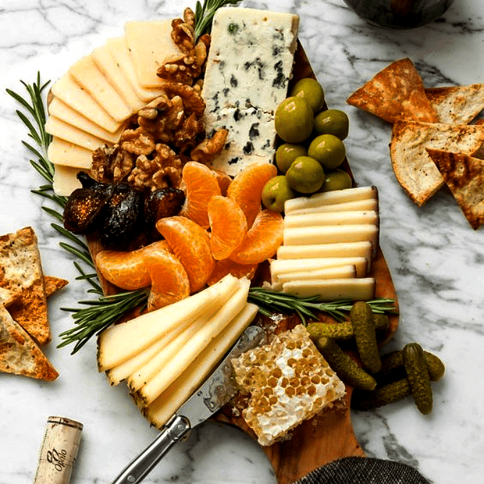 tabla de quesos, embutidos, charcutería, uvas, salami, jamón serrano, con estilo navideño
