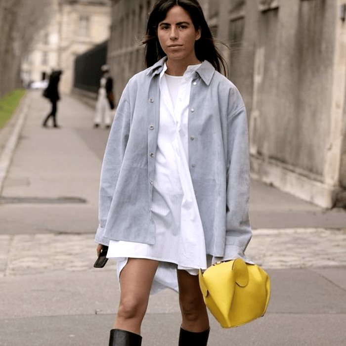 mujer usando un vestido blanco y camisa gris con botas negras