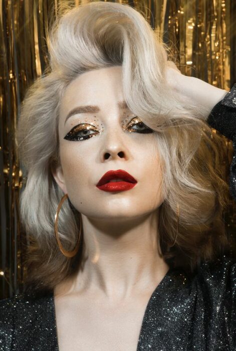 Chica con maquillaje en dorado, delineado doble y labial rojo; Maquillajes para celebrar Navidad