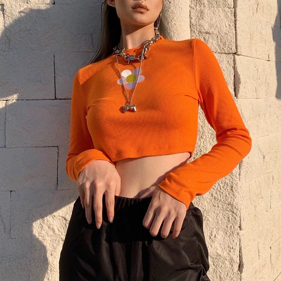 Chica llevando un top naranja con estampado de margarita; Ideas para usar color naranja en tu outfit