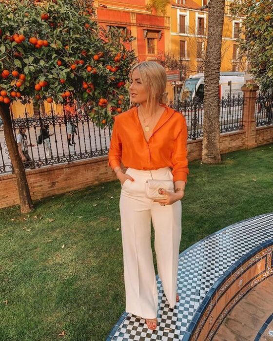 Chica usando una blusa de satín en color naranja con pantalón sastre; Ideas para usar color naranja en tu outfit