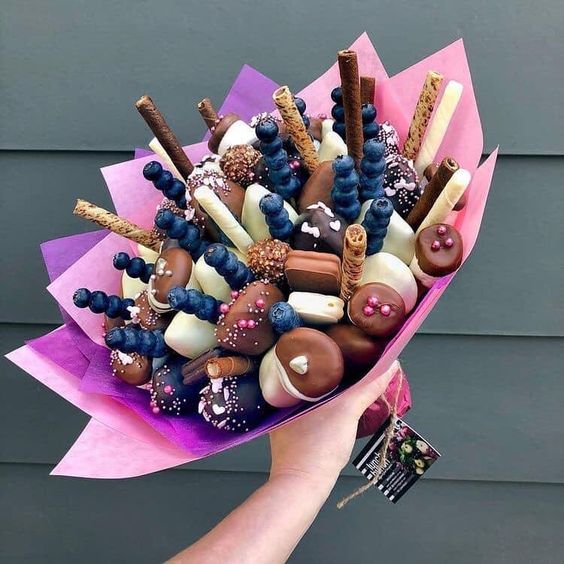 Ramos de galletas, arándanos y palitos crujientes envuelto en papel china color rosa y morado