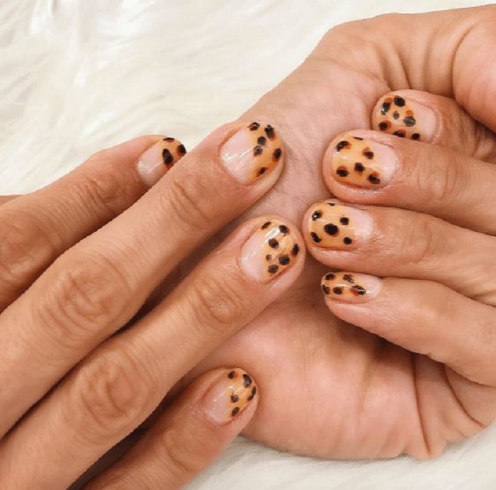 Manicura en diseño animal print con base transparente y color mostaza, en punta diagonal
