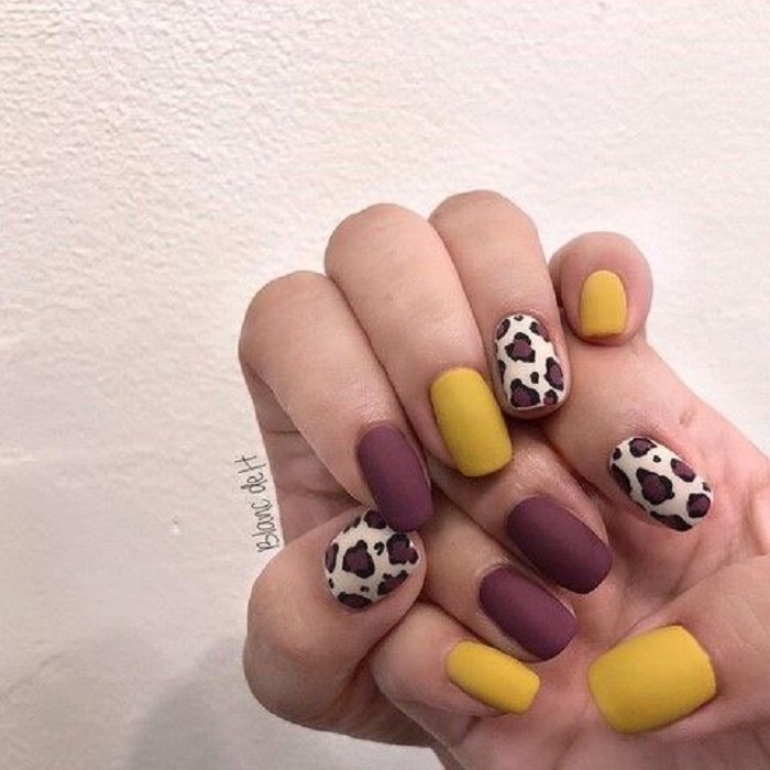 Manicura en diseño animal print en colores vino y mostaza con decoraciones