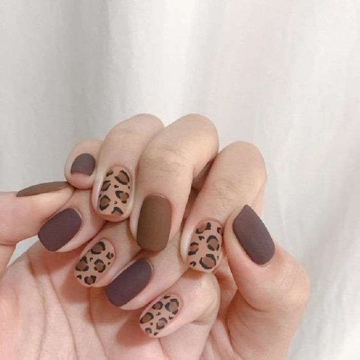 Manicura en diseño animal print en colores tierra con detalles en índice y anular