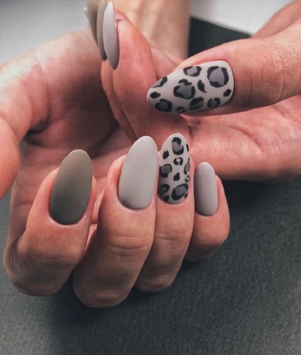 Manicura en diseño animal print en tonos grises con decoraciones en el anular y pulgar
