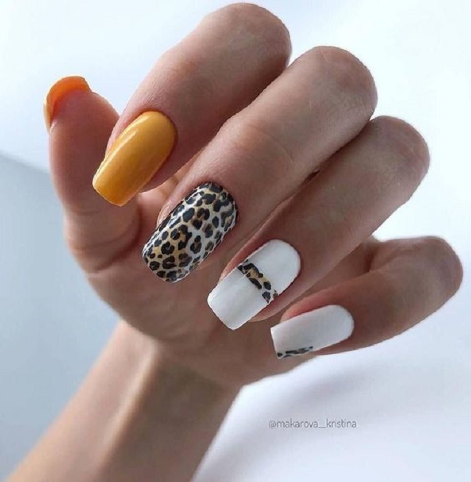 Manicura en diseño animal print en naranja, amarillo y blanco, decorada en dedos medio y anular