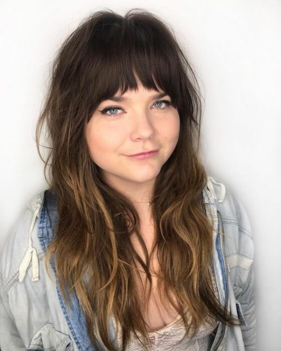 Chica de cara redonda con cabello largo en capas con fleco degrafilado