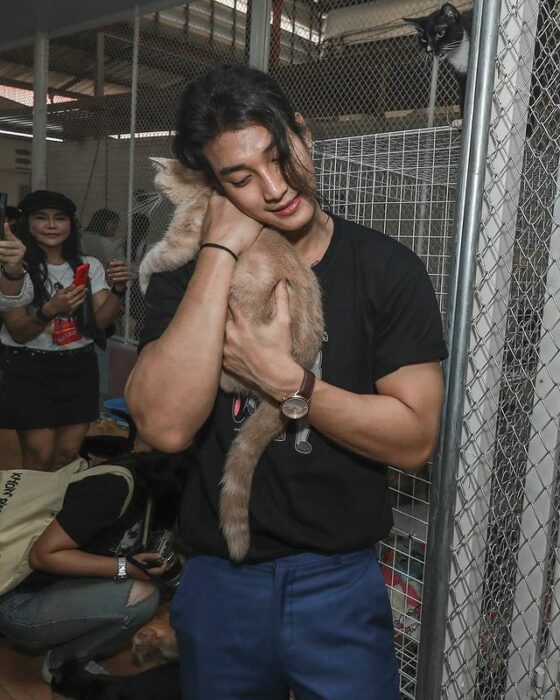 Paing Takhon abrazando a un gato café claro con una camiseta negra