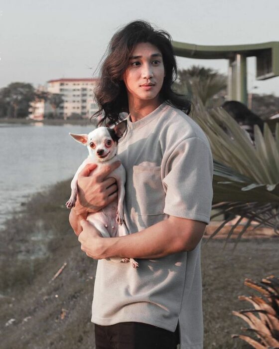 Paing Takhon con una camiseta gris sosteniendo un perro chihuahua blanco 