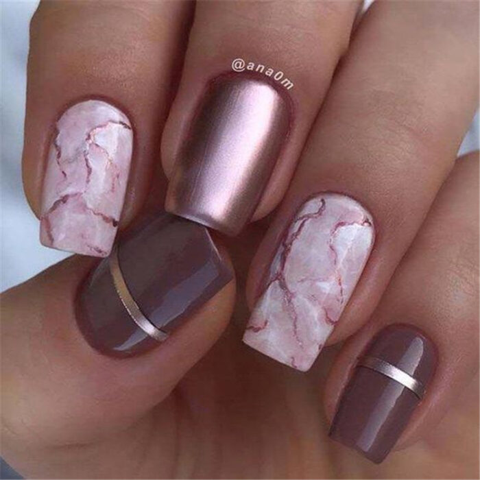 Chica con las uñas en un diseño metálico de color rosa con diseños en mármol