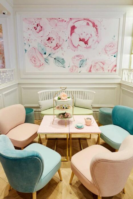 Restaurante con paredes blancas y tapiz de flores rosas, con sillones en varios colores