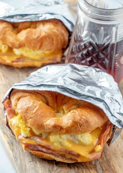 Croissant relleno de jamón, queso y huevo envuelto en papel