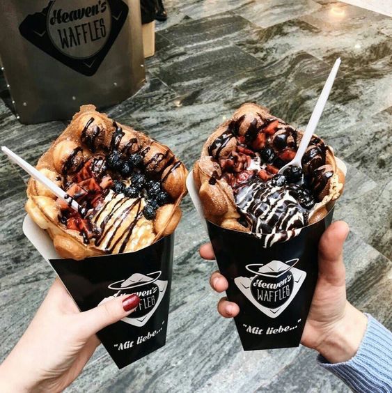 Conos de papel negro de waffles con fresas, moras y Nutella