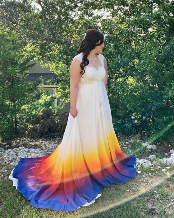 Novia con peinado de media coleta rizada con vestido largo con escote en corazón y mangas de tirantes y la parte inferior con un degradado de colores