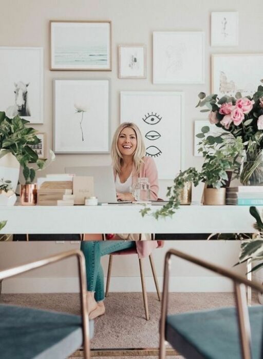 Chica trabajando en su escritorio con varias macetas de plantas