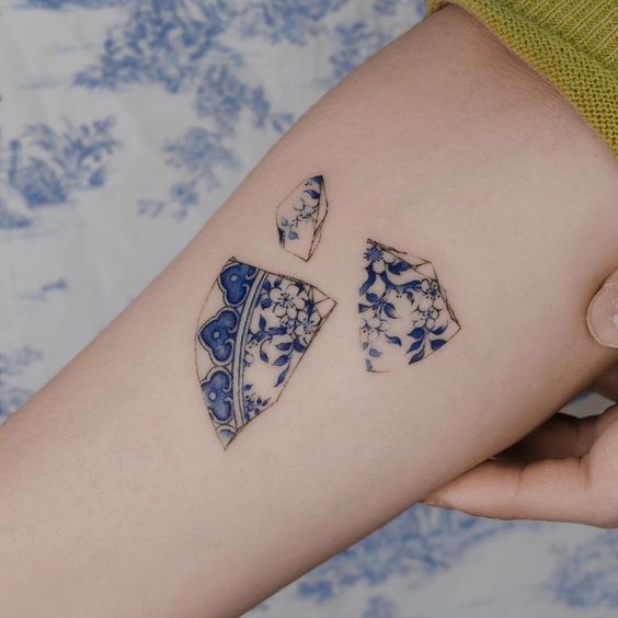 Tatuaje en el brazo de plato rojo de vajilla blanca con azul