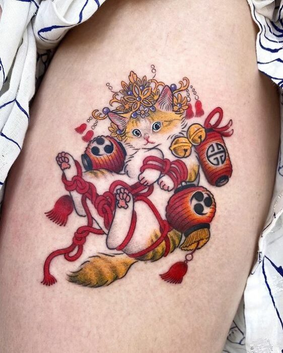 Tatuaje de gatito blanco con amarillo envuelto en lazos rojos