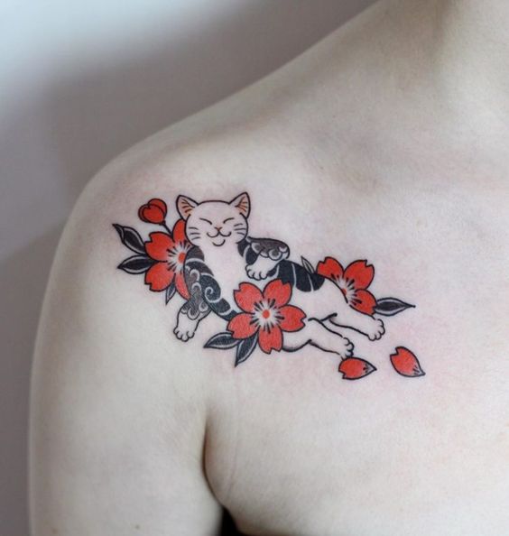Tatuaje en la clavícula de gatito blanco acostado rodeado de flores de cerezo rojas