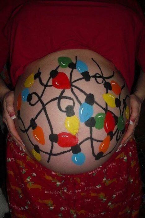 Mujer con la pancita pintada con luces navideñas; Ideas para pintar tu panza de embarazada este diciembre