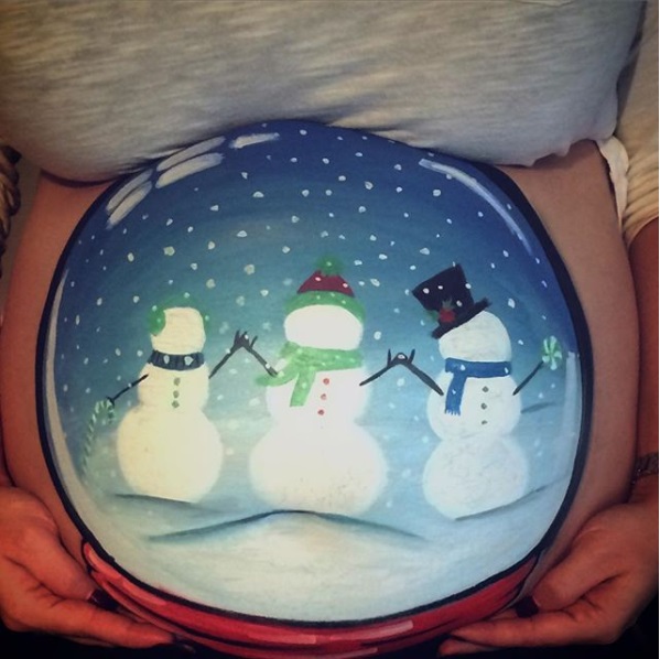 Chica con la pancita pintada en esfera de nieve con muñecos de nieve; Ideas para pintar tu panza de embarazada este diciembre