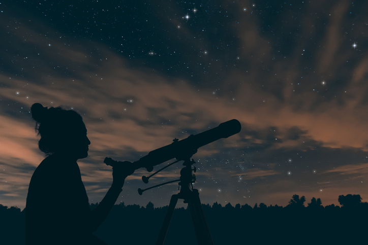 Chica observando las estrellas por un telescopio