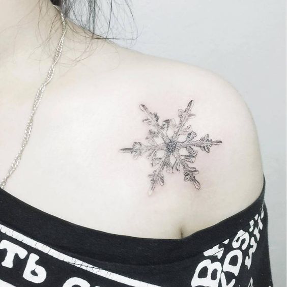 Chica con tatuaje de copo de nieve; Tatuajes miniatura para las que aman la Navidad