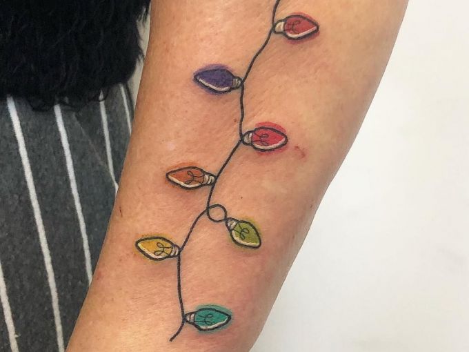 Chica con tatuaje navideño en forma de guirnalda de luces; Tatuajes para las chicas que aman Navidad