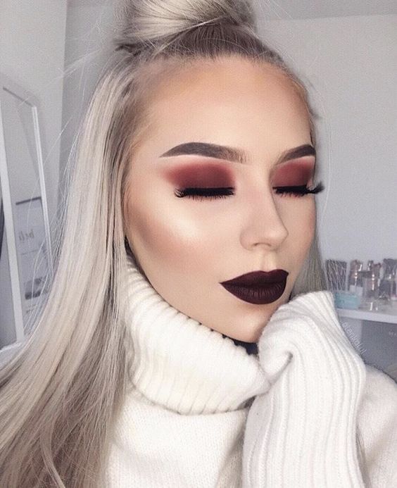 Chica rubia de cabello largo rubio con labial rojo oscuro y sombras ahumadas en color rojo
