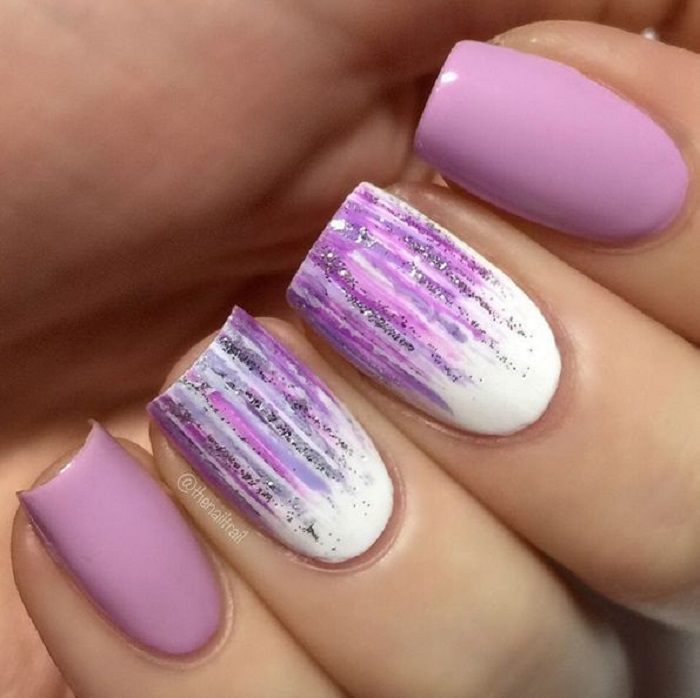 Manicura en tonos lilas con brillos y tonos blancos