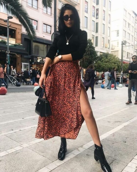 Chica con maxi falda naranja y camisa de cuello alto negro; Ideas para usar camisa de cuello alto