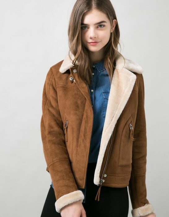 Chica con chaqueta camel peluda, blusa azul y jeans negros